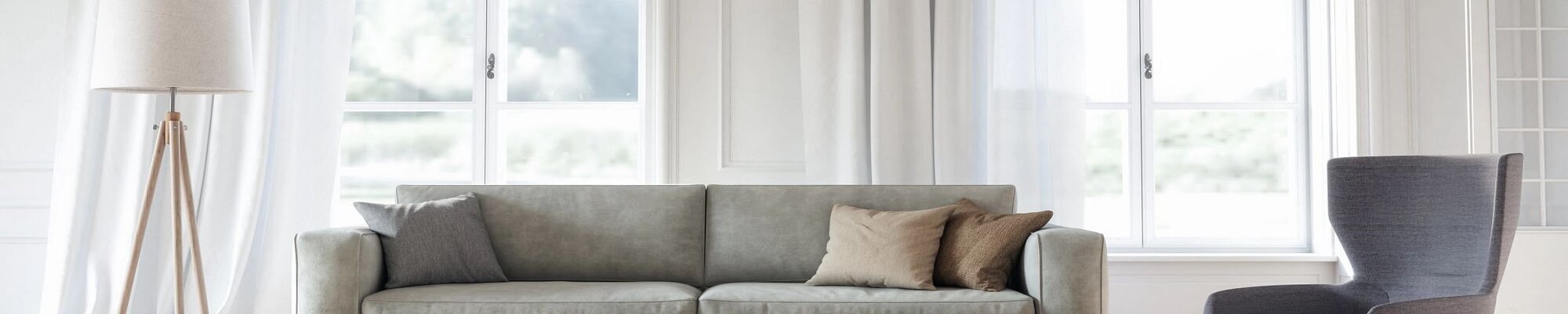 Bright living room with a gray couch and large windows with white curtains - Success Floor Covering LLC in Oakland, MD